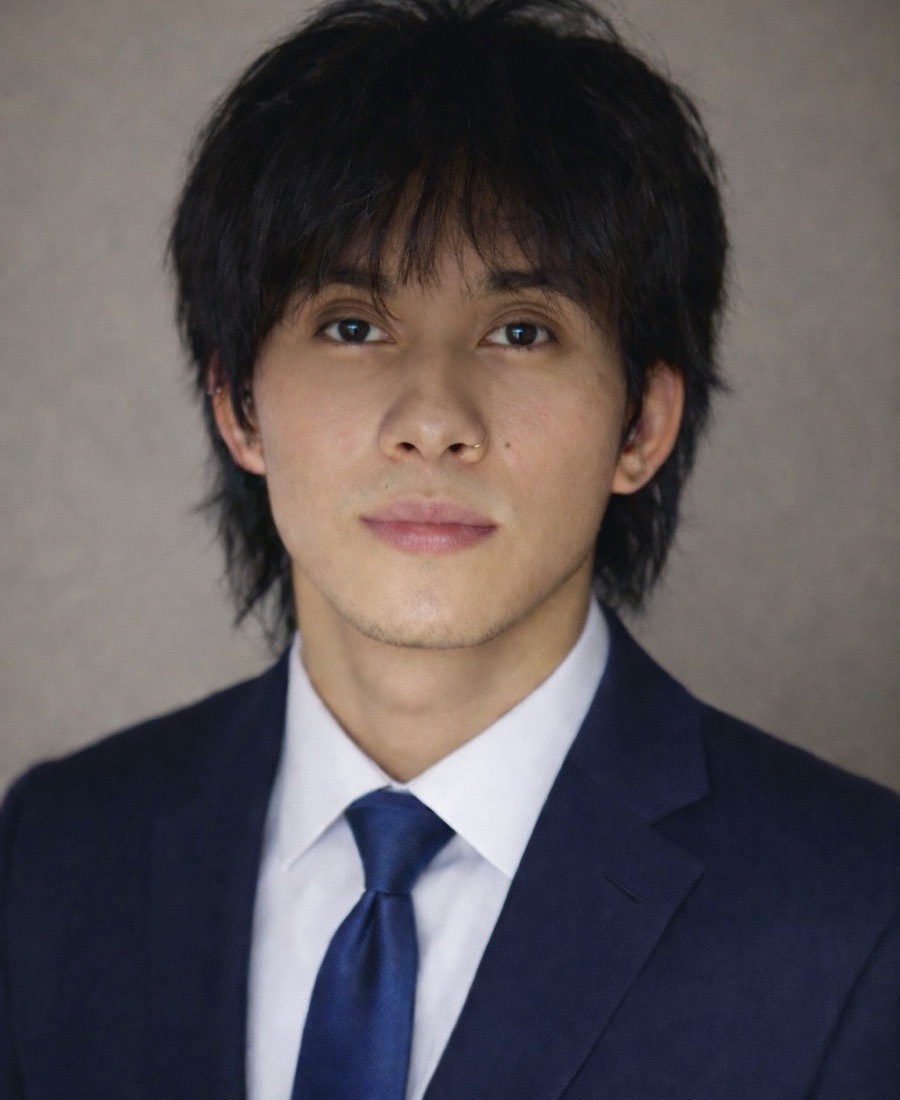 Justis Peppin, head and shoulders, in a navy suit and tie against a grey backdrop.