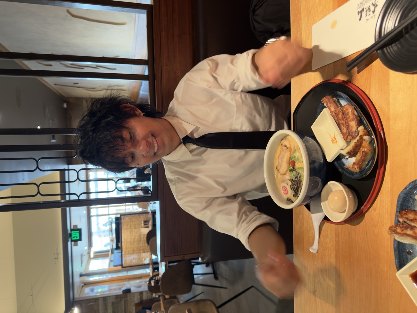 Justis at a ramen counter with a bowl of tonkotsu ramen and gyoza.