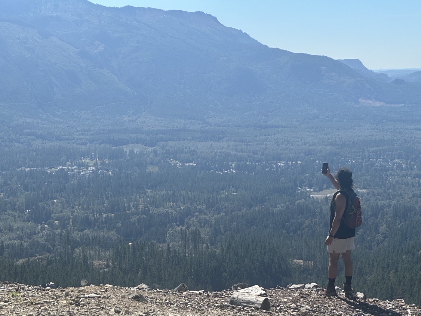 Justis photographing a wide valley view from a ridge above the tree line.