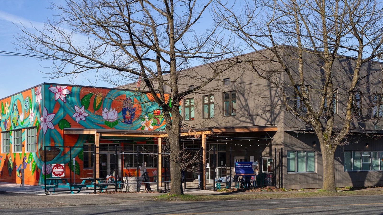 Rainier Valley Food Bank's building on a clear winter day, its corner wrapped in a mural of flowers and vegetables.